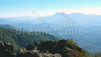 山地景观。 远处，群山的山脊可以透过薄雾看到。 前景是石头。